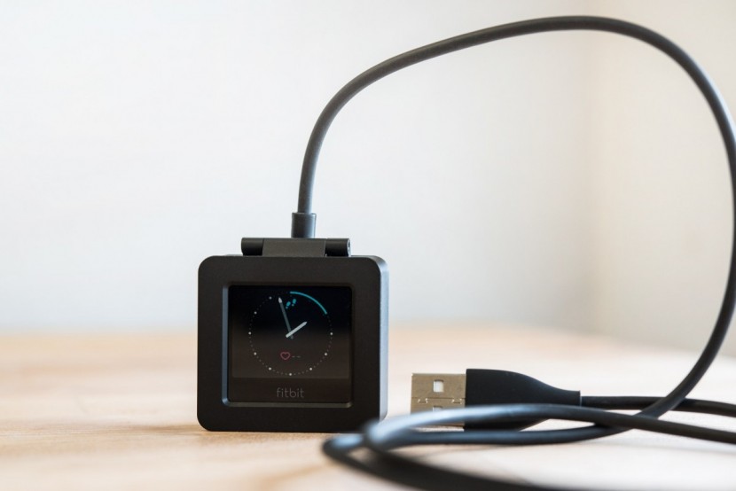 fitbit blaze - the blaze is removed from its band to charge in a specialized charger.