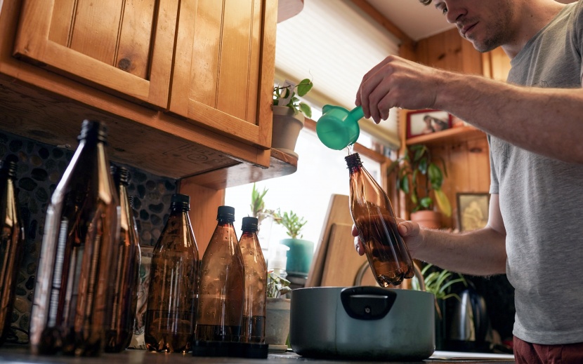 home brewing kit - pouring sanitizing solution into the mr. beer 16-oz bottles before...